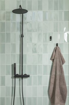 there is a towel hanging on the wall next to a shower head and hand held shower faucet