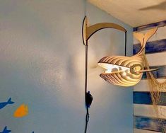 a fish shaped light hanging from the side of a wall next to a blue painted wall