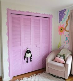 a child's room with pink shutters and a chair in front of the door