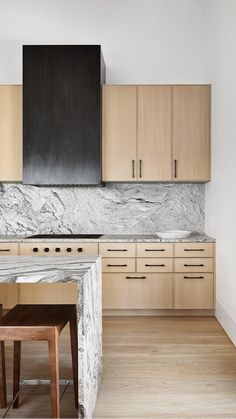 a kitchen with marble counter tops and wooden cabinets, along with two stools in front of the stove