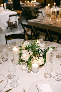 the table is set with white and green flowers, candles, and napkins on it