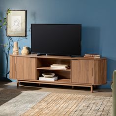 a flat screen tv sitting on top of a wooden entertainment center in a living room