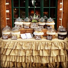 a table topped with lots of jars filled with food next to a green window sill