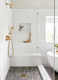 a bath room with a tub a shower head and a mirror on the wall next to a window