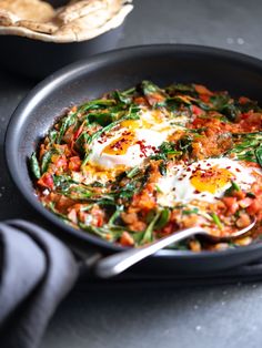 a skillet filled with eggs and spinach on top of a black countertop