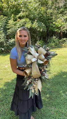 a woman is holding a wreath in her hands and smiling at the camera while standing on grass