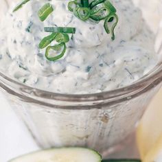 cucumber and sour cream in a glass container with sliced limes on the side