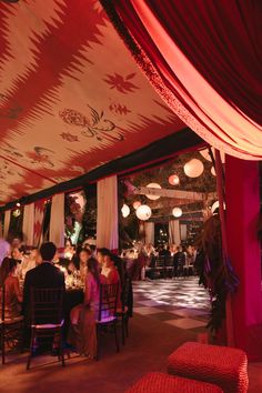 people sitting at tables in a restaurant with red and white drapes on the ceiling