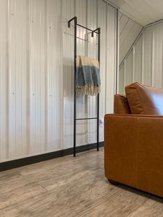 a brown leather couch sitting in front of a metal wall with a towel rack on it