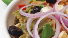 a white bowl filled with pasta and olives