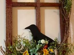 a black bird sitting on top of a window sill filled with flowers and greenery