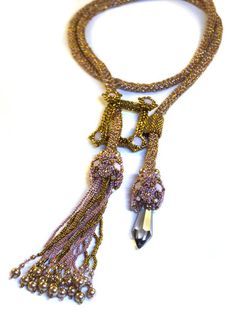 "My favorite element about making lariats is how versatile they are to wear. This lariat is no exception. On each end of a long netted chain, create two intricate ends sparkling with Swarovski chatons and embellished with pearls, adding fringe and a long chandelier point for two different designs. Stitch a \"frame\" like component with chatons on four corners as a focal point, that can be used in several different ways when wearing the lariat. Supplies Needed: 11/0 Seed Beads 11/0 Cylinder Beads Adjustable Lariat Beaded Necklaces For Parties, Gold Lariat Necklace With Dangling Beads, Handmade Elegant Lariat Necklace, Elegant Handmade Lariat Necklace, Gold Beaded Dangle Lariat Necklace, Gold Beaded Lariat Necklace With Dangle, Adjustable Beaded Lariat Necklace For Parties, Bohemian Lariat Necklace With Dangling Beads, Elegant Handmade Lariat Beaded Necklace