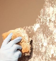 a person in blue gloves and white gloves is cleaning the wall with a sponge on it