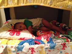 a small child laying in a bed next to pillows and blankets on top of it