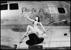 a black and white photo of a woman on the nose of an airplane