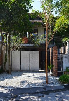 an entrance to a house with trees in the front yard and gravel on the ground