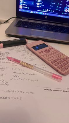 a calculator and pen sitting on top of a piece of paper next to a laptop computer