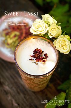 a glass filled with liquid and flowers on top of a table