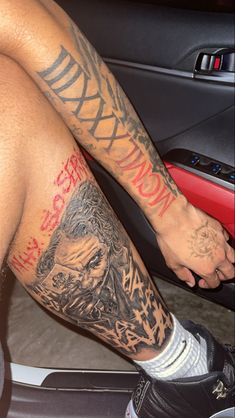 a man with tattoos on his legs sitting in a car