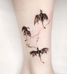 a woman's leg with a tattoo on it that has two bats flying through the air