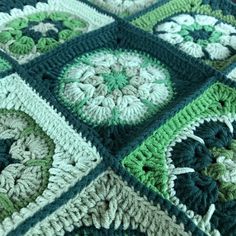 a green and white crocheted blanket with flowers on it