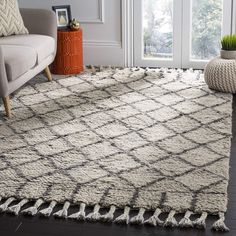 a living room area with a couch, chair and rug on the floor in front of a window