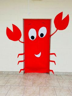 a red door with a cartoon character on it's face and arms, standing in front of a white brick wall