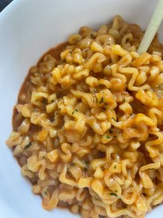 a white bowl filled with macaroni and cheese on top of a wooden spoon