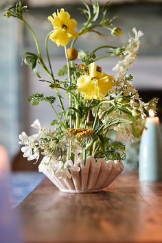 a vase filled with yellow flowers sitting on top of a table next to a candle