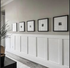 a living room with white paneling and pictures on the wall