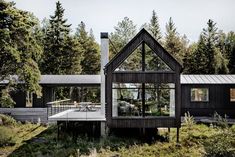 the house is surrounded by tall trees and has glass walls on both sides that allow natural light into the room