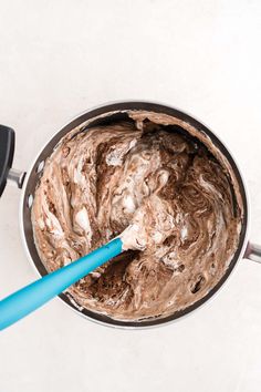 a blue spatula in a metal bowl filled with chocolate frosting