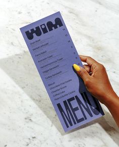 a person holding a menu in their left hand and writing on it with a yellow marker