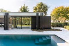 a modern house with a swimming pool in the foreground and an outdoor dining area on the other side