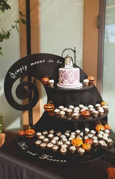 a three tiered cake and cupcake display on a table