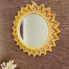 a mirror hanging on the side of a wall next to a vase with flowers in it