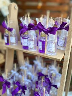 purple and white candies in small bottles on a wooden shelf with ribbons tied around them