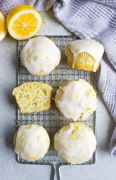 lemon muffins with icing on a cooling rack next to sliced lemons