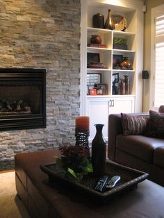 a living room filled with furniture and a fire place in front of a stone wall