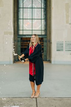 a woman in a black dress is holding a wine bottle and spraying it with water