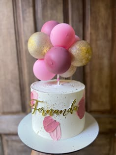 a white cake with pink and gold balloons on top