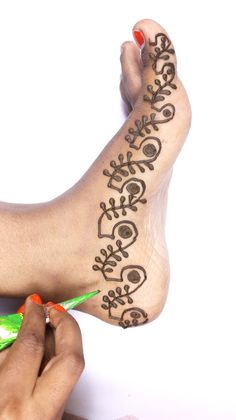 someone is doing henna on their foot