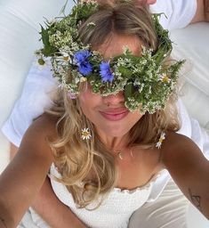 a woman laying on top of a bed wearing a wreath of flowers in her hair