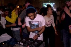 a dj mixing music at a party with people in the background