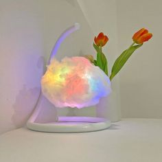 a vase with flowers in it sitting on a table next to a white light fixture