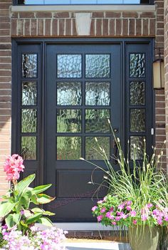 a black front door with two planters and flowers