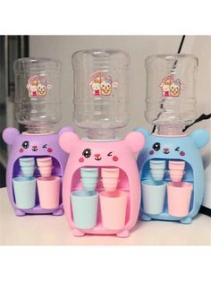 three water dispensers with bear faces on them, one is pink and the other is blue