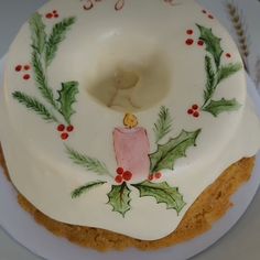 a cake decorated with holly and a lit candle on it's side sitting on a plate