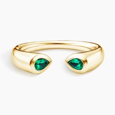 a gold ring with two green stones on it