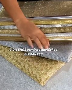 a woman is placing her hand on some gold and silver bags that are stacked together